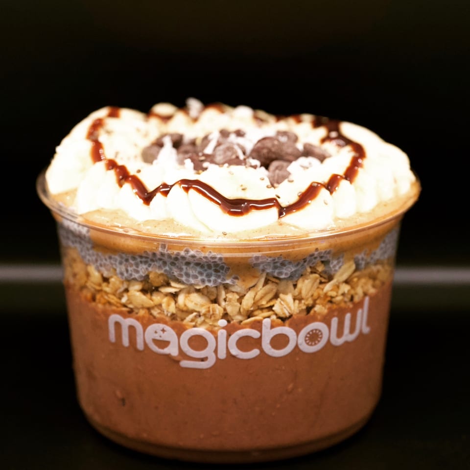 Magic Bowl chocolate smoothie bowl with granola, chia seeds, whipped cream, chocolate chips, and syrup.
