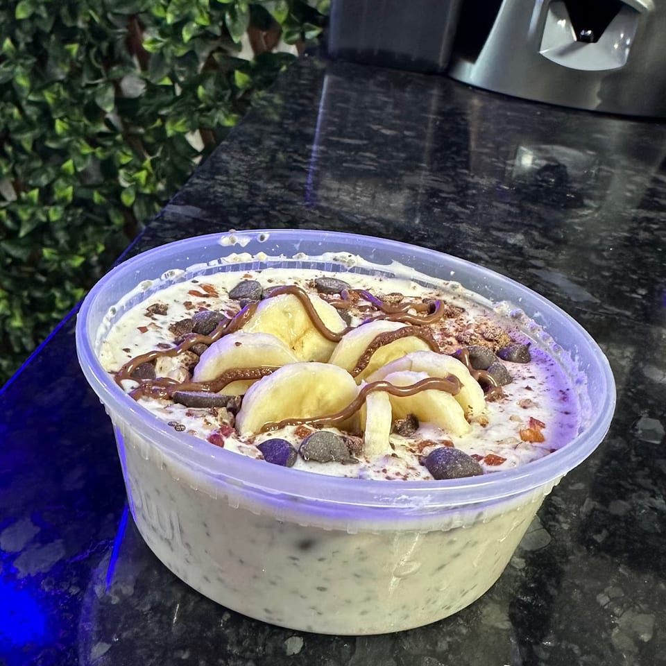 Overhead view of a dessert bowl with banana slices, chocolate chips, and chocolate drizzle.
